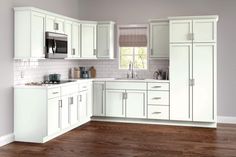 an empty kitchen with white cabinets and wood flooring, is pictured in this image