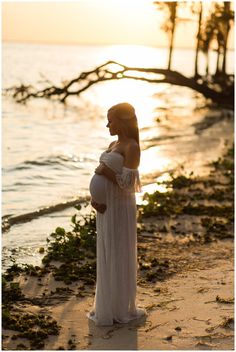 a pregnant woman standing on the beach at sunset with her belly wrapped around her waist