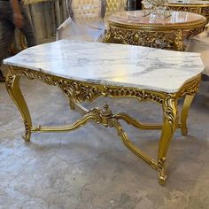 a marble top coffee table with gold trimmings in a room filled with chairs