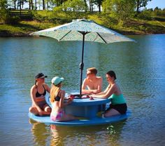 three people are sitting on a small boat in the water with an umbrella over it