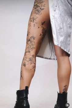 the legs and ankles of a woman with tattoos on her body, wearing high heeled boots