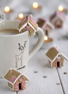 some cookies are in the shape of houses next to a cup of hot chocolate and marshmallows