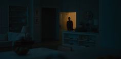 a man standing in the doorway of a living room at night with his back to the camera