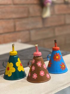 three small vases with flowers painted on them