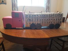 a pink toy train sitting on top of a wooden table next to a white couch