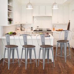 three metal stools sit in front of a kitchen island