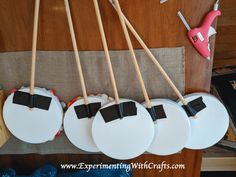 four drums are hanging from the wall with wooden sticks in front of them and some other things on the table