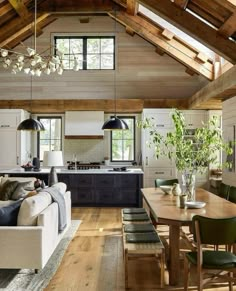 a living room filled with furniture next to a kitchen and dining room table in front of an open floor plan