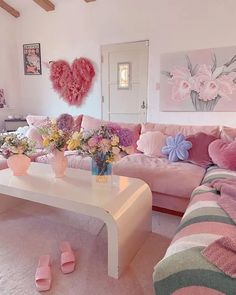 a living room filled with furniture and flowers on top of a white coffee table in front of a pink couch