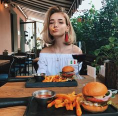 a woman sitting at a table with two plates of food in front of her face