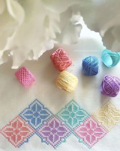 four balls of yarn sitting on top of a table next to white flowers and a crochet doily