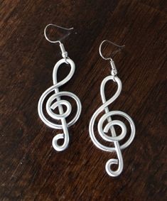 silver treble earrings sitting on top of a wooden table