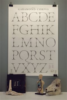 an art work with letters and figures on a table next to a framed poster that reads,'garamond corves '