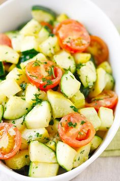 a white bowl filled with cucumbers and tomatoes