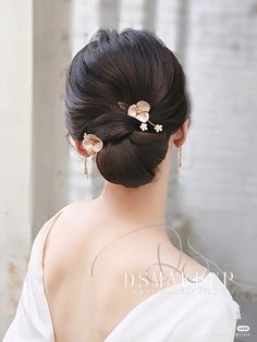 a woman with her back to the camera, wearing a white dress and gold earrings