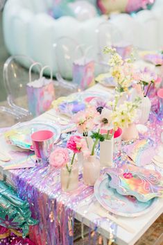 a table set with plates, cups and vases filled with flowers on top of it