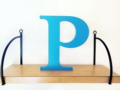 a wooden shelf with two black metal brackets and a blue letter p on the top