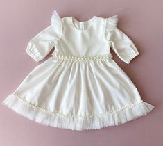 Baptism dress for baby girl with pearls. The colour of this dress is ivory.  There are tulle ruffles on the shoulders and pearl belt on the waist. Fabric-natural cotton.  The price is only for the dress.  We can sew matching booties, bloomers, headband with the same lace as on the dress. headband: https://www.etsy.com/listing/1277763367/pearl-headband-baby-girl-flower-girl?click_key=9393e6bb703f386c0c50cd01bd709eaa8bb3fb9f%3A1277763367&click_sum=d890857f&ref=shop_home_active_23&frs=1&sts=1 Booties: https://www.etsy.com/listing/1289288259/booties-with-pearls-for-baby-girl?click_key=113a40180a248241c7aecfc9d3b7cb88de5f260b%3A1289288259&click_sum=44c05677&ref=shop_home_active_1&frs=1&sts=1 bloomers: https://www.etsy.com/listing/1289301209/baptism-bloomers-baby-girl-bloomers?click_key=1b9d14d9 Toddler Baptism, Girl Baptism Dress, Christening Dress Baby Girl, Girls Baptism Dress, Baptism Dress Baby Girl, Dress For Baby Girl, Pearl Belt, Tulle Ruffles