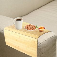 a cup of coffee sitting on top of a wooden table next to a bowl of fruit