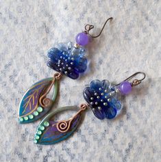 Jewel toned earrings featuring green, blue and purple leaf shaped enameled charms with gold details. They are topped with ruffled blue lampwork beads, sterling beads and purple quartz beads. Simple copper swirls dangle from the center. These stylish earrings measure 3 3/8 inches in total length and hang on niobium earring hooks. Return to shop: bstrung.etsy.com More links where you can find me: Facebook: http://www.facebook.com/bstrung Pinterest: http://pinterest.com/bstrung Instagram: https://w Handmade Blue Whimsical Flower Earrings, Unique Hand Painted Purple Earrings, Whimsical Handmade Blue Flower Earrings, Artsy Purple Drop Earrings, Whimsical Nickel-free Purple Earrings, Whimsical Purple Nickel-free Earrings, Unique Purple Flower Earrings, Whimsical Blue Nickel-free Earrings, Blue Enamel Flower Earrings As Gift