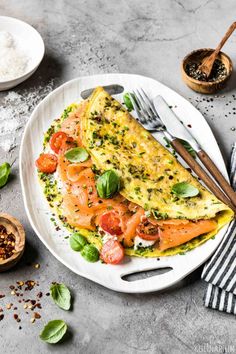 an omelet with salmon and spinach on a plate next to some spices