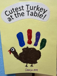 a turkey handprinted on a yellow paper with the words cutest turkey at the table