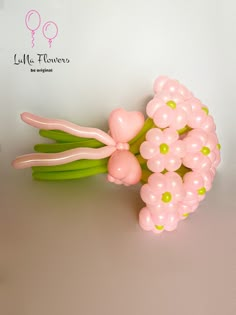 a bunch of balloons sitting on top of a table next to some green stems and pink flowers