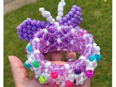 a person holding up a purple and white beaded bracelet