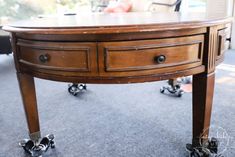 a wooden table with two drawers and casteors on it's wheels, in front of a couch