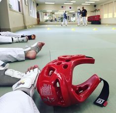 two people laying on the floor with their feet propped up next to a red helmet