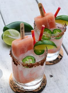 two glasses filled with watermelon and cucumber garnish on wooden coasters