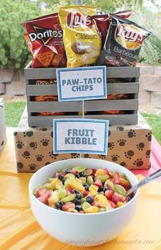 a bowl of fruit is sitting on a table next to some boxes with dog treats