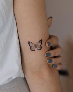 a woman's arm with a butterfly tattoo on the left side of her arm