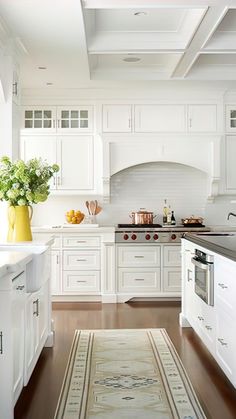 a large kitchen with white cabinets and wood flooring, along with an area rug