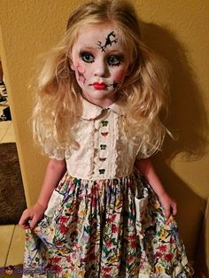 a doll with makeup on it's face standing next to a wall