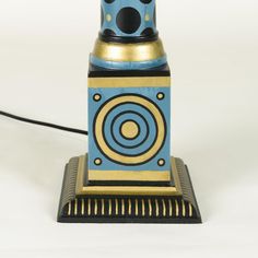 a small blue and gold clock sitting on top of a table next to a black cord