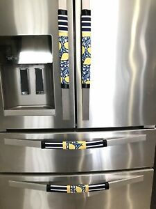 a stainless steel refrigerator with yellow and blue napkins on the handles, in a kitchen