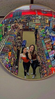 two women are taking a selfie in the mirror at a grocery store with their cell phone