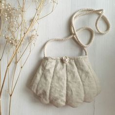 a white purse sitting next to some dried flowers