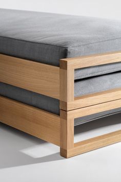 a wooden bed frame with grey sheets on it