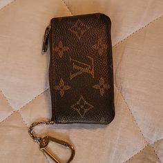 a brown purse with a keychain on top of it and a white quilt