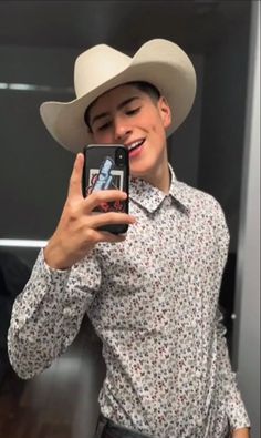 a man wearing a cowboy hat taking a selfie with his cell phone in front of him