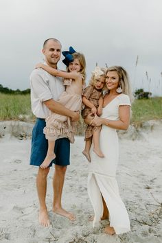 a man and woman holding two children on the beach