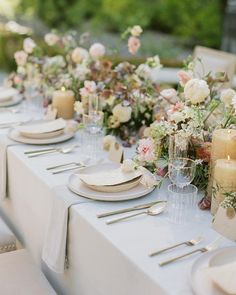 the table is set with candles, plates and place settings for an elegant dinner party