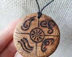 a hand holding a wooden pendant with designs on it