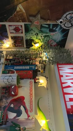 there are many books on the shelf with lights around them and spider - man figurines