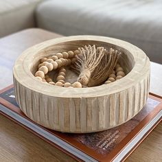 a wooden bowl sitting on top of a table next to a book and a white couch