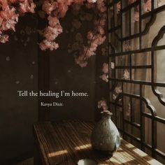 a vase sitting on top of a wooden table next to a wall covered in flowers