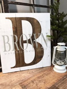 a wooden sign sitting on top of a table next to a potted pine tree