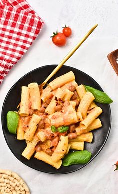 a black plate topped with pasta and spinach